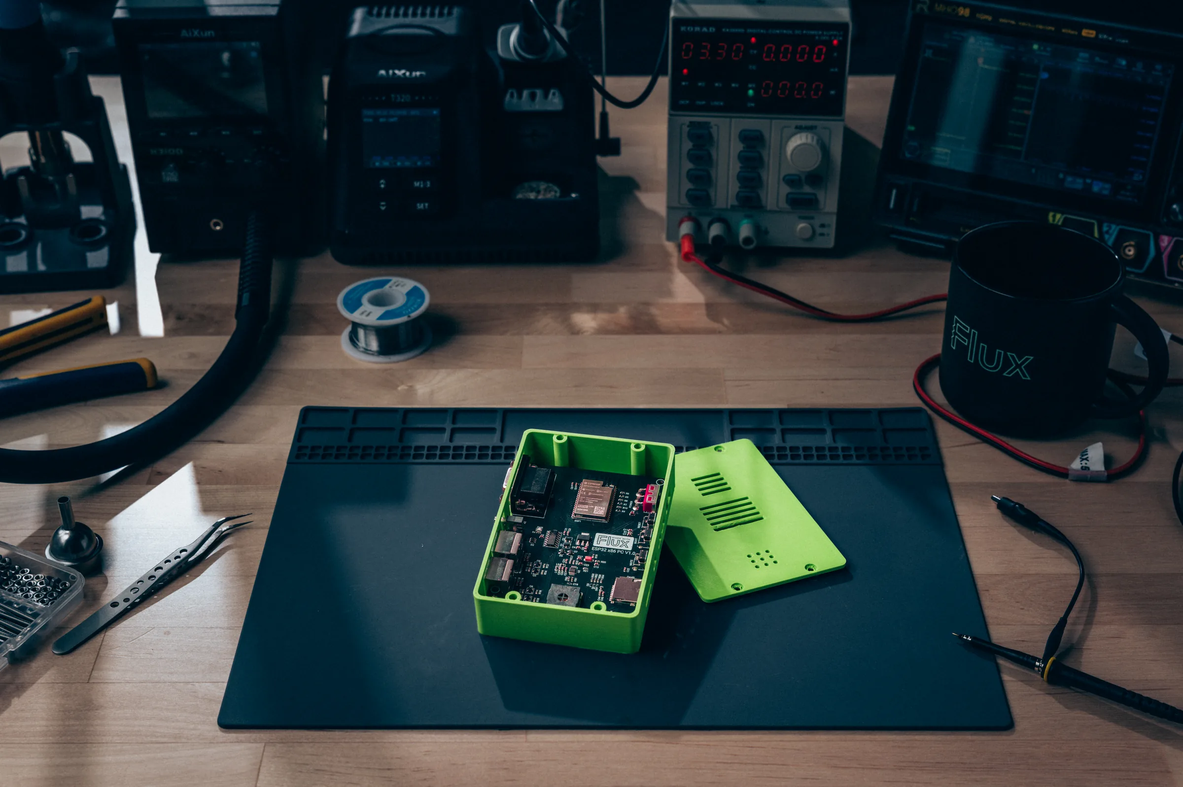 A board in a green 3D-printed enclosure on an electronics bench