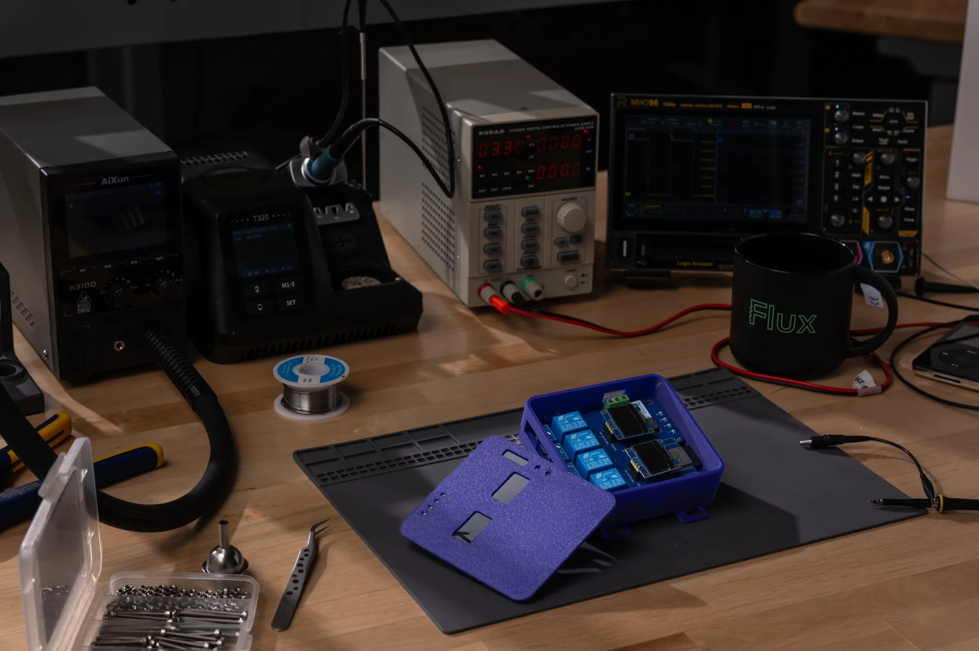 Flux-designed relay board in a purple 3D-printed enclosure on a workbench beside a Flux mug